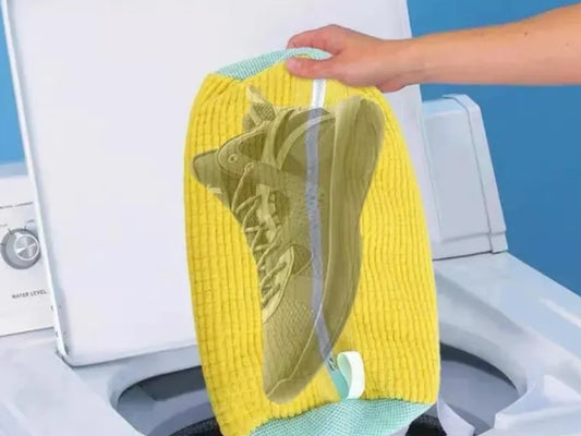Sneaker visible through the yellow shoe laundry bag going into a washing machine